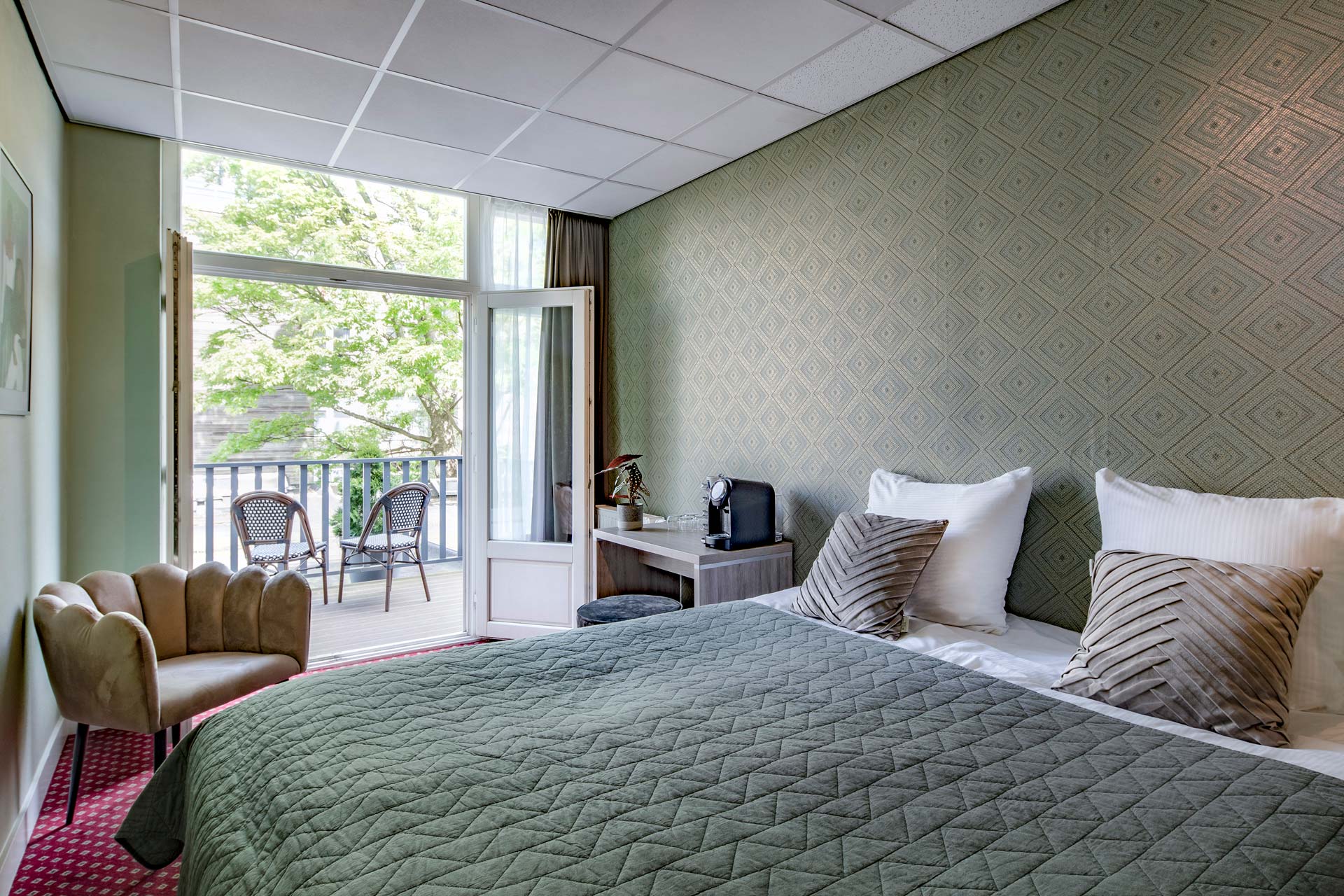 A double room with the balcony doors open onto the trees