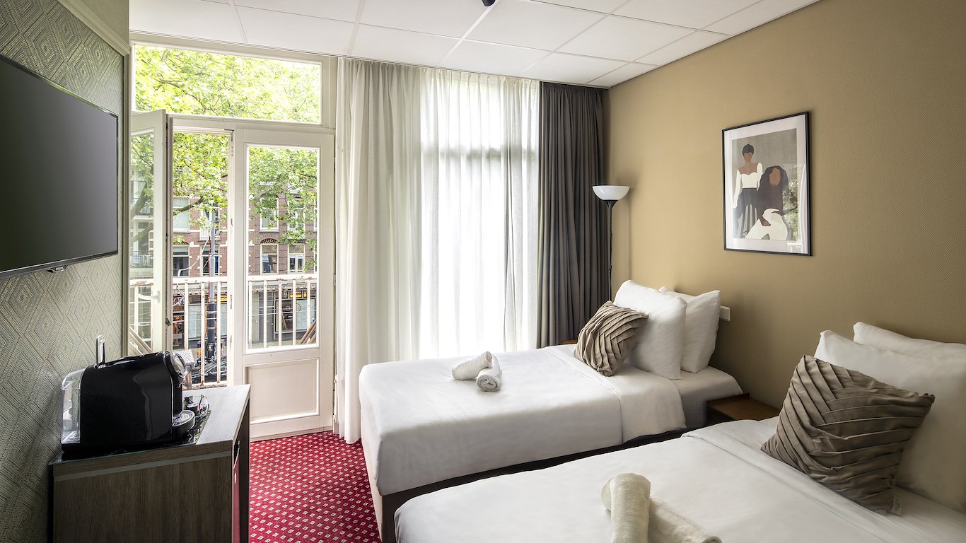 Two single beds with the balcony doors open onto the trees on Ceintuurbaan, the coffee machine in the foreground